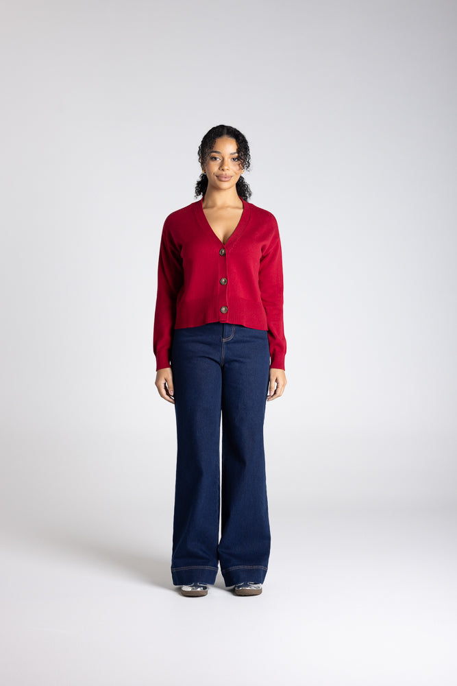 Person wearing a red cardigan and blue jeans on a white background